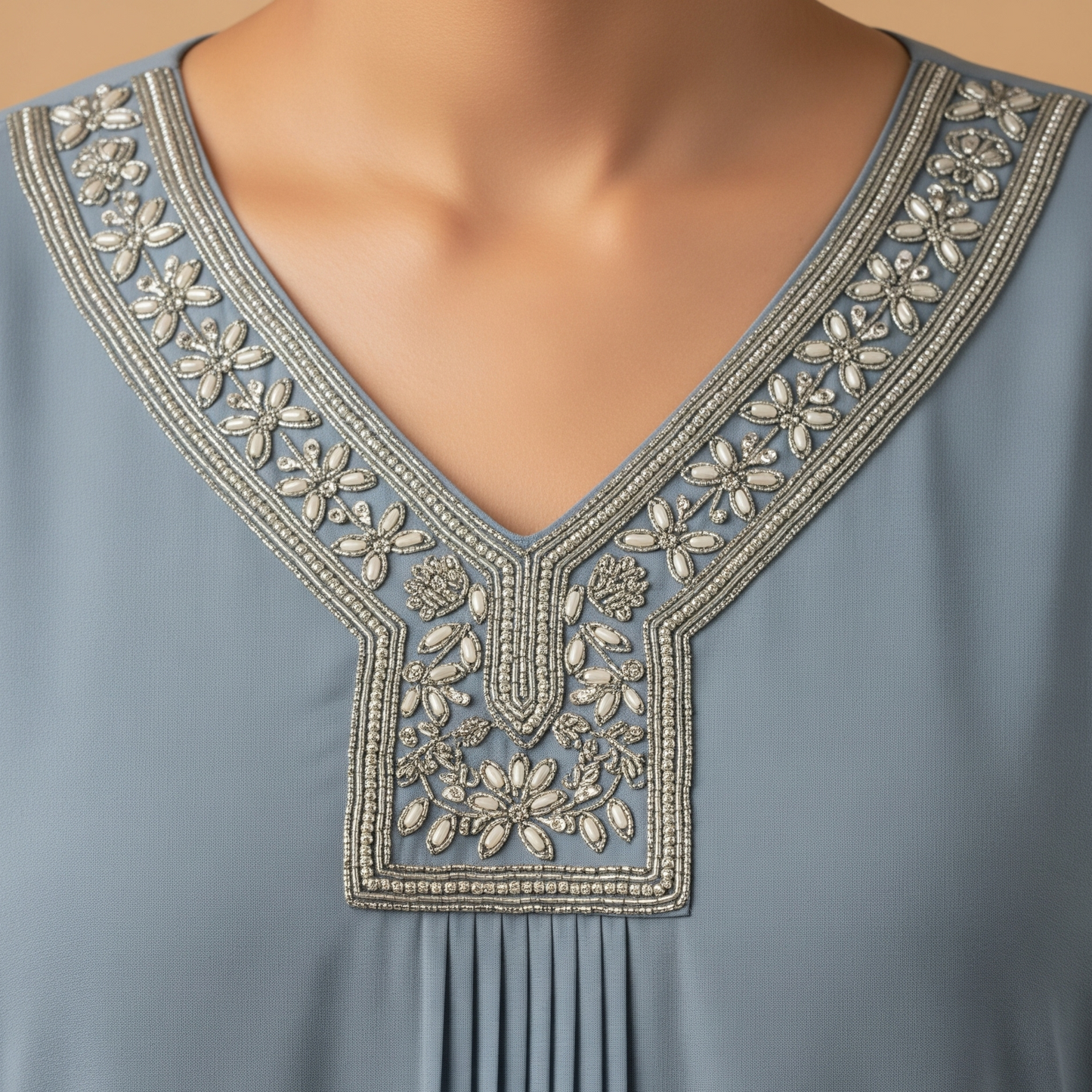 A close-up view of the v-neckline on the Alaya Kaftan, detailing the exquisite floral hand-embroidery crafted with silver and white beads.