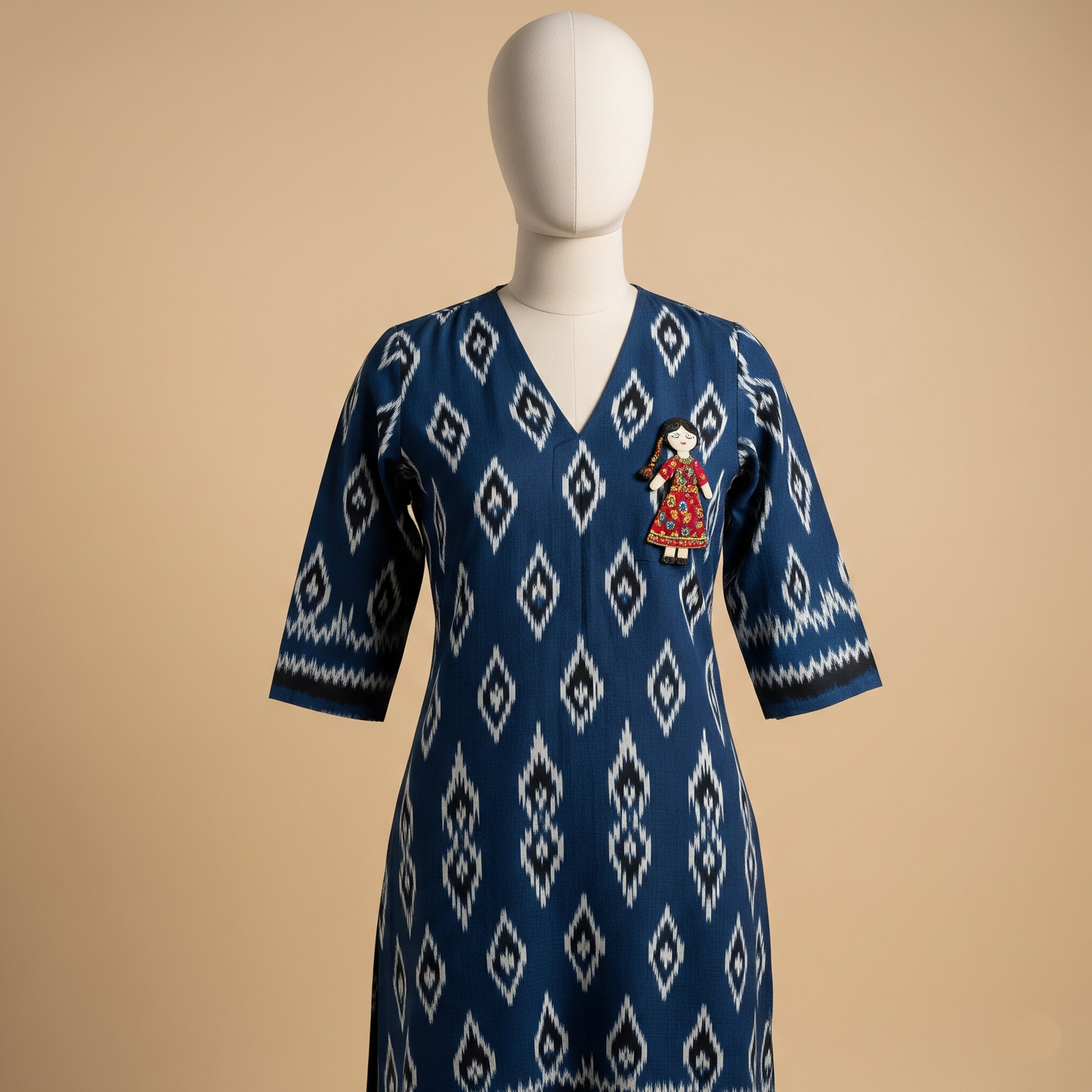Indigo blue Ikat print kurta with a V-neck and a small, handcrafted doll brooch, displayed on a mannequin.